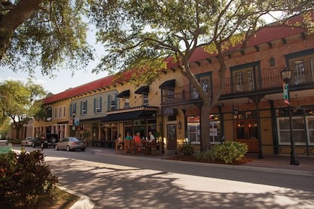 Explore the Gulf Island Ferry Stops Old Main Street Bradenton with an oak tree canopy and vintage looking brick buildings