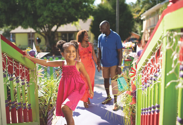 Home a girl in a pink dress and a man and woman walking down a sidewalk
