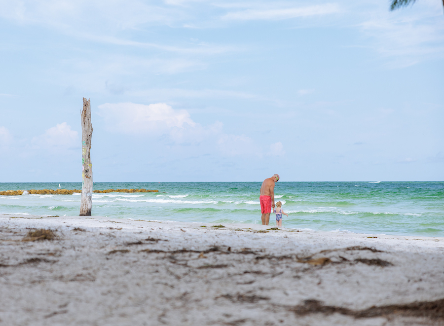 Family Adventures: Memories Made on the Gulf grandfather and small child holding hands on the shore of Beer Can Island