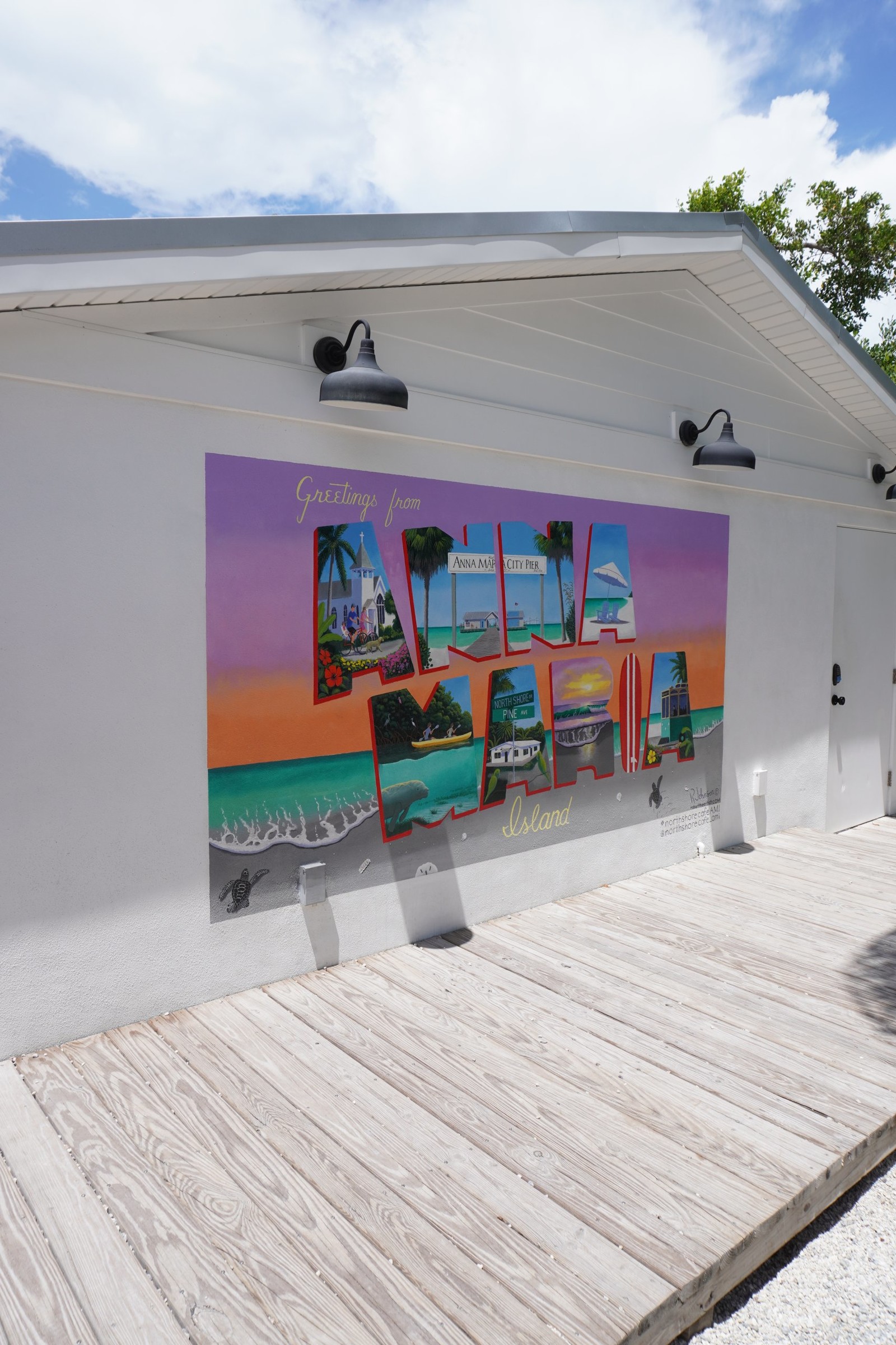Explore the Gulf Island Ferry Stops a vintage inspired postcard painted on a wall reading GREETINGS FROM ANNA MARIA ISLAND
