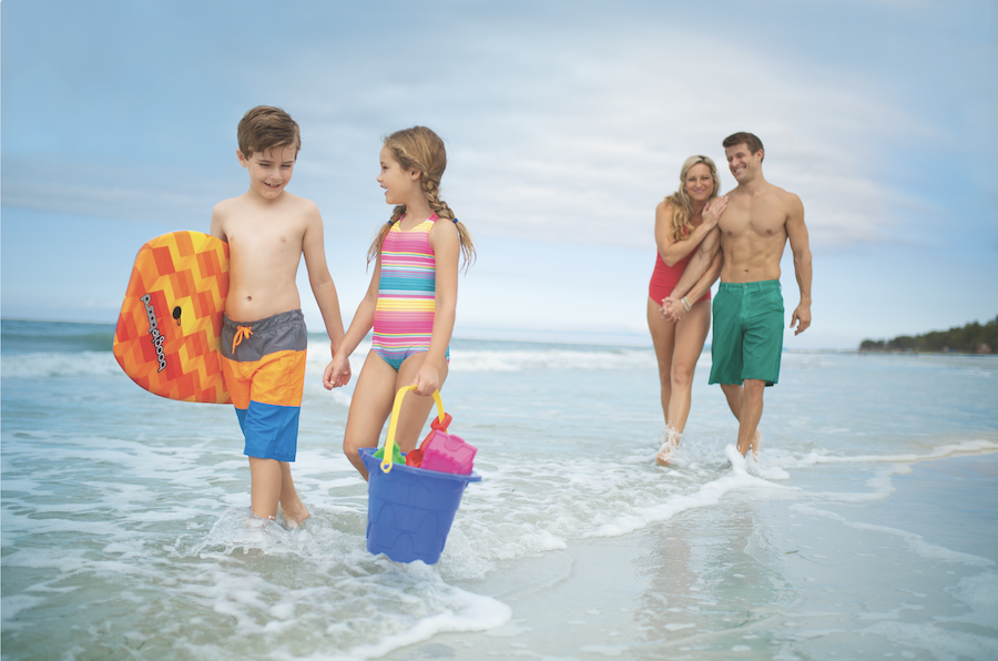 Family Adventures: Memories Made on the Gulf family of four wading in the waves on a beach